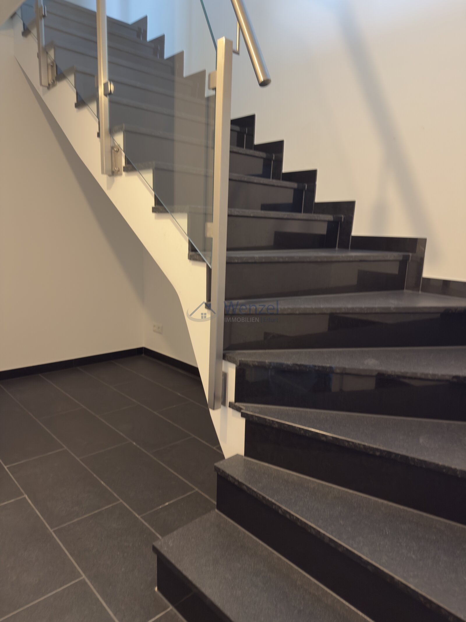 Moderne Treppe mit Glasgeländer und hochwertiger Metallhandlauf Moderne Treppe mit Glasgeländer und hochwertiger Metallhandlauf