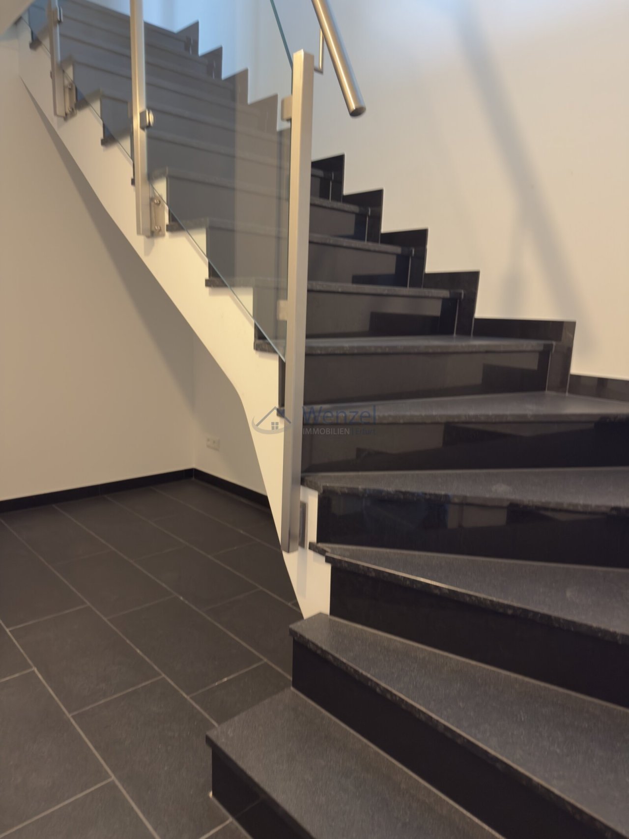 Moderne Treppe mit Glasgeländer und hochwertiger Metallhandlauf Moderne Treppe mit Glasgeländer und hochwertiger Metallhandlauf
